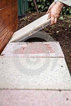 Man is laying quadratic tiles in the garden