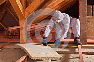 Man laying rockwool panels in the attic of a house photo