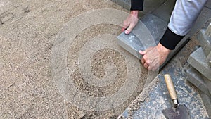 Man laying rows of concrete square pavers or tiles