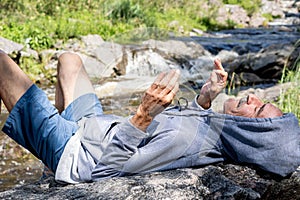 a man laying on the side of a rock and waving his hands