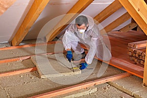 Man laying thermal insulation layer - cutting the panels