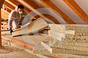 Man laying thermal insulation layer under the roof