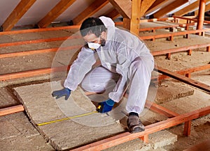 Man laying thermal insulation layer under the roof