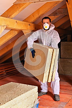 Man laying thermal insulation layer under the roof