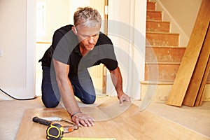 Man laying wood panel flooring during a house refurbishment