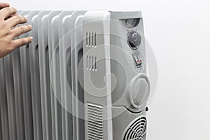 Man lays his hands for oil heater for getting warm on white background.