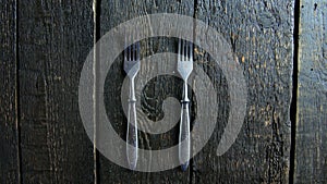 Man lays out the forks on a wooden bg