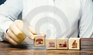 A man lays in a row blocks with symbols of business shops, offices and factories. Building a successful business empire.