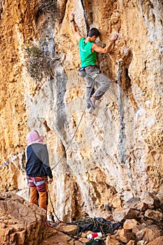 Man lead climbing on cliff, belayer watching hi