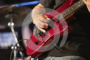 Man lead guitarist playing electrical guitar on concert stage.