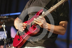 Man lead guitarist playing electrical guitar on concert stage.