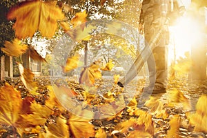 Man with a leaf blower is removing fallen leaves from the sidewalk