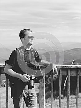 A man lean against a railing with mountain ridge background