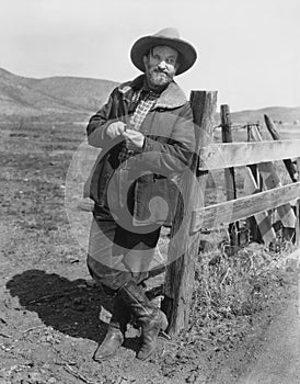 Man leaning against fence post