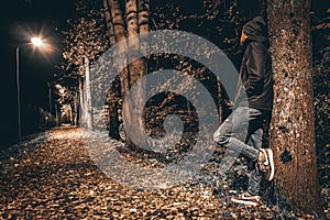 A man leaning against a tree, full road with leaves. Latvian city Valmiera