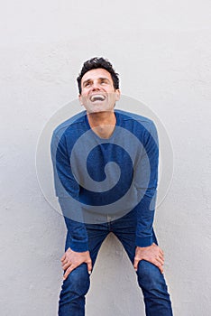 Man leaning against wall with hands on knees and laughing