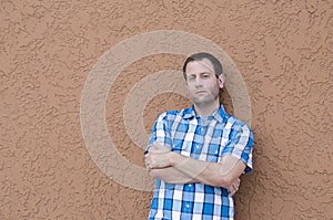 Man leaning against a wall with his arms crossed.