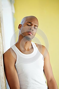 Man leaning against wall at home with eyes closed