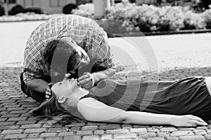 Man leaning over a woman in the street and checking her life functions