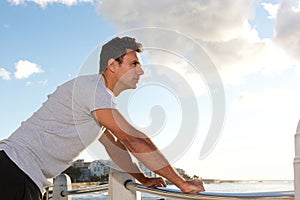 Man leaning on railing outside and looking at sea