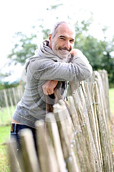 Man leaning on wood fence