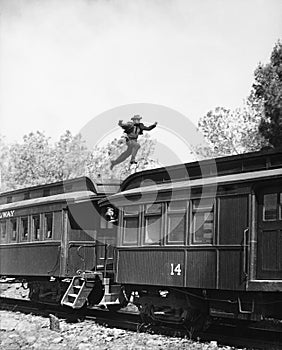 Man leaping across the roof of railroad cars