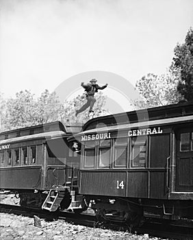 Man leaping across the roof of railroad cars photo