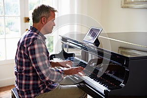 Man Learning To Play Piano Using Digital Tablet Application