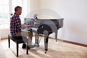 Man Learning To Play Piano Using Digital Tablet Application