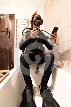 A man learns through online lessons with his smartphone to dive, in the bathtub of his house. Home confinement