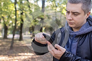 A man in a leather jacket looks at the phone in the middle of the forest. Social media immersion, orienteering, and phone stress