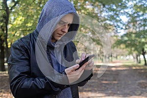 A man in a leather jacket looks at the phone in the middle of the forest. Social media immersion, orienteering, and phone stress