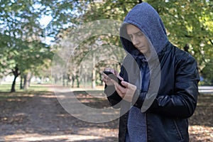 A man in a leather jacket looks at the phone in the middle of the forest. Social media immersion, orienteering, and phone stress