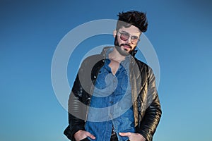 Man in leather jacket standing with hands in pocke