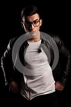 Man in leather jacket wearing glasses with hands on waist