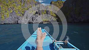 Man legs on banca boat approaching tropical island. travel, relaxation and vacations concept