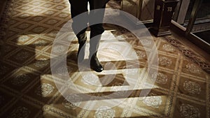 Man legs in brown sneakers walking on blue carpet on long corridor in home interior. Close up man feet walking on long
