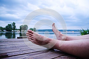 Man legs on a dock while relaxing on seaside.