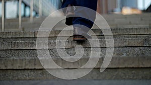 man legs are going up over stone stairs in city, closeup view, elegant shoes and pants