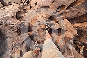 Man legs with hiking shoes standing on rugged rock of grand canyon in Thailand