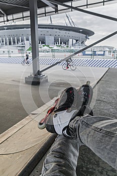 man legs in roller skates sits on a ramp in skatepark.