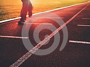 Man legs in running shoes on red racetrack on outdoor stadium.