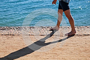 Man legs on sand. Male feet walking on beautiful sandy beach of hotel resort in Egypt, doing and leave footprints in sand.