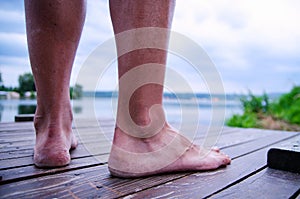 Man legs standing on a dock while relaxing on seaside.