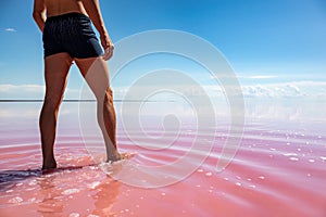 Man legs view walking in pink salt lake water