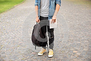 Man legs in yellow sneakers, wearing grey t-shirt, black skinny jeans at university campus in autumn.