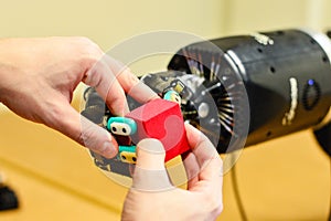 Man Lets Mechanical Robot Hand Holding a Red Cube in the Research Laboratory.