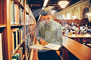 Man in the library reading room took the book from the shelf and reading photo