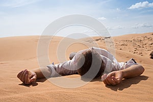 Man lie alone in the sunny desert. He is lost and out of breath. No water and energy.