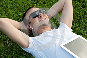 Man lie with tablet on the grass